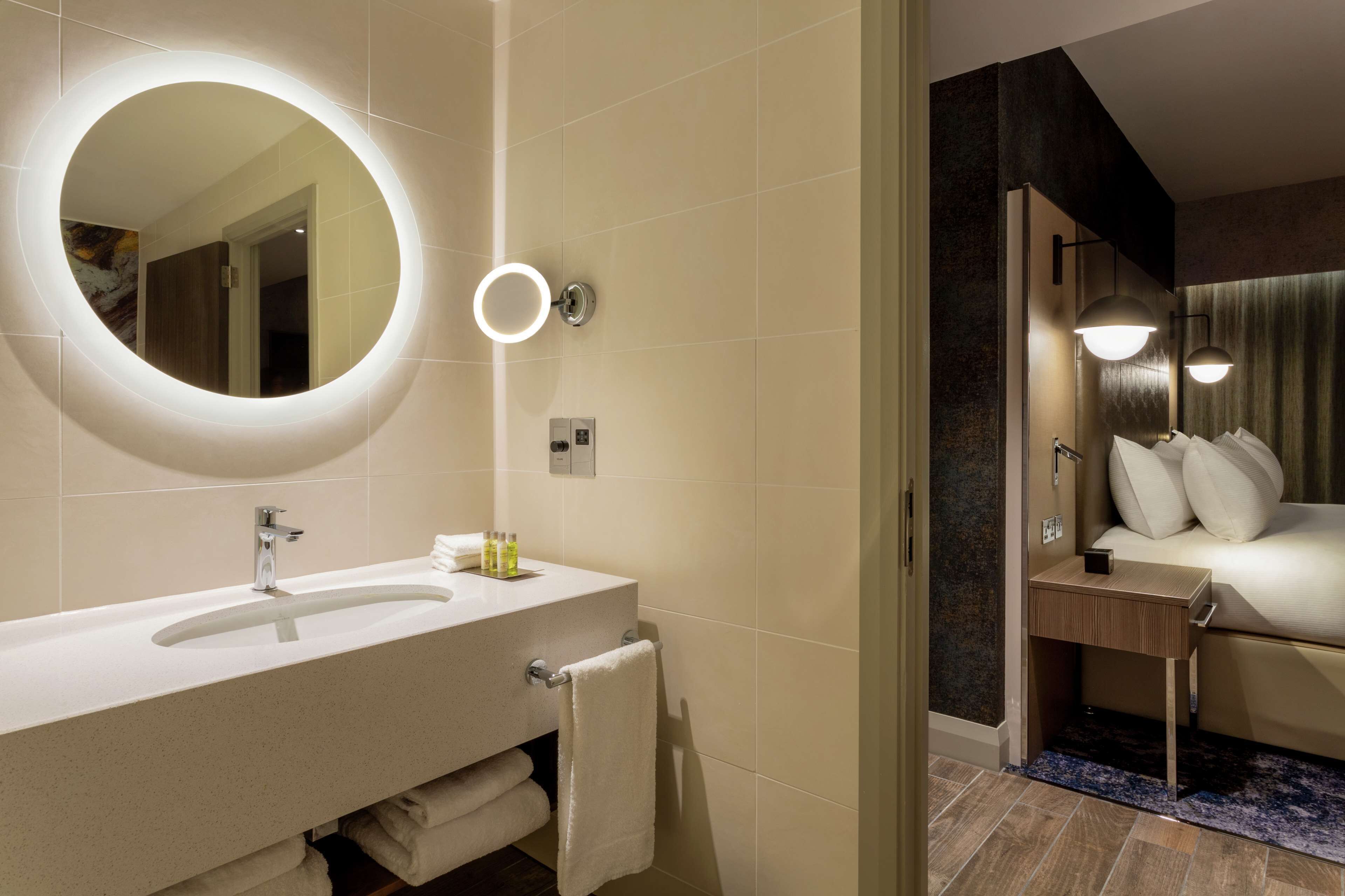 A modern bathroom with a round mirror, a sink, and a vanity.