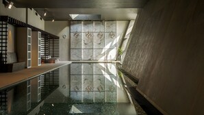 A modern interior with a reflective pool, geometric wall tiles, and a minimalist staircase. - Hilton Aberdeen TECA (Aberdeen)