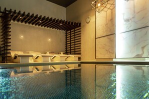 A modern indoor pool area with seating and a wall with a clock. - Hilton Aberdeen TECA (Aberdeen)