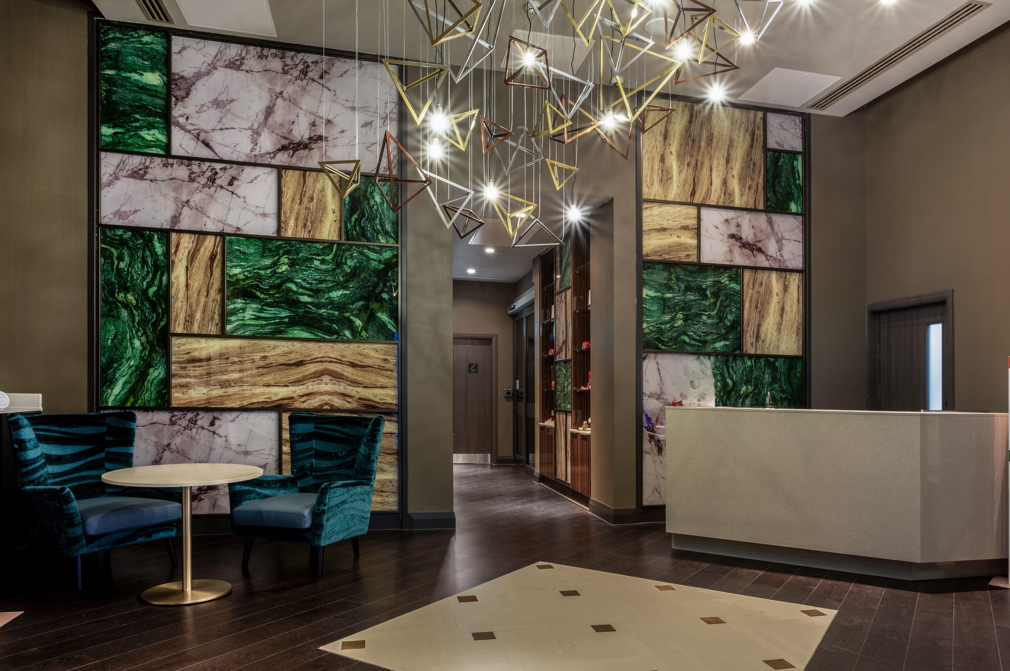 A lobby with a reception desk, seating area with chairs, and a patterned wall.