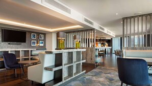 A modern living area with a flat-screen TV, seating, a coffee table, and a decorative shelf. - Hilton Aberdeen TECA (Aberdeen)