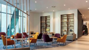 A modern lobby with colorful seating, a large bookshelf, and a view of the outside. - Hilton Aberdeen TECA (Aberdeen)