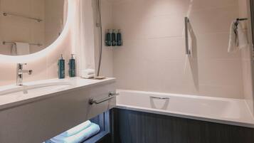 A modern bathroom with a large mirror, a bathtub, and a shower.