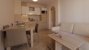 A modern kitchen with a dining area, a sofa, and a small table with decorative items. - Luxury Apartment in Anastasia Palace (Sunny Beach)