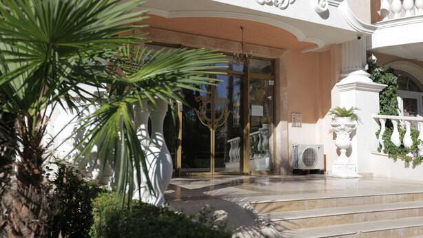 A grand entrance with a curved staircase, a glass door, and a white balustrade. - Luxury Apartment in Anastasia Palace (Sunny Beach)