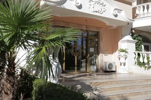 A grand entrance with a curved staircase, a glass door, and a white balustrade.