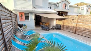 Un jardin avec une piscine, une terrasse couverte et une clôture en bois.
