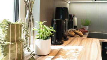 Un comptoir de cuisine avec une machine à café, une plante en pot et un vase à rayures.