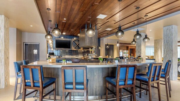 A modern kitchen with a central island, bar stools, and pendant lighting. - Cambria Hotel Milwaukee Downtown (Milwaukee)