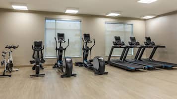 A gym with various cardio machines, including treadmills and stationary bikes, arranged in rows.