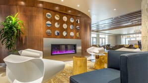 A modern lobby with a curved wooden wall, a fireplace, and contemporary seating. - Cambria Hotel Milwaukee Downtown (Milwaukee)