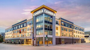 A modern multi-story hotel with a prominent "Cambria" sign on the corner, featuring large windows and a clean, contemporary design. - Cambria Hotel Milwaukee Downtown (Milwaukee)