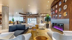 A modern hotel lobby with a seating area, a fireplace, and a wall decorated with circular mirrors. - Cambria Hotel Milwaukee Downtown (Milwaukee)