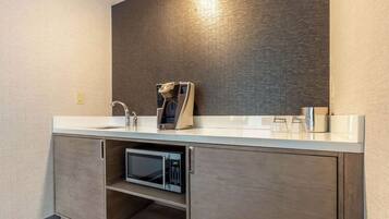 A modern bathroom with a built-in microwave, a digital scale, and a large mirror.