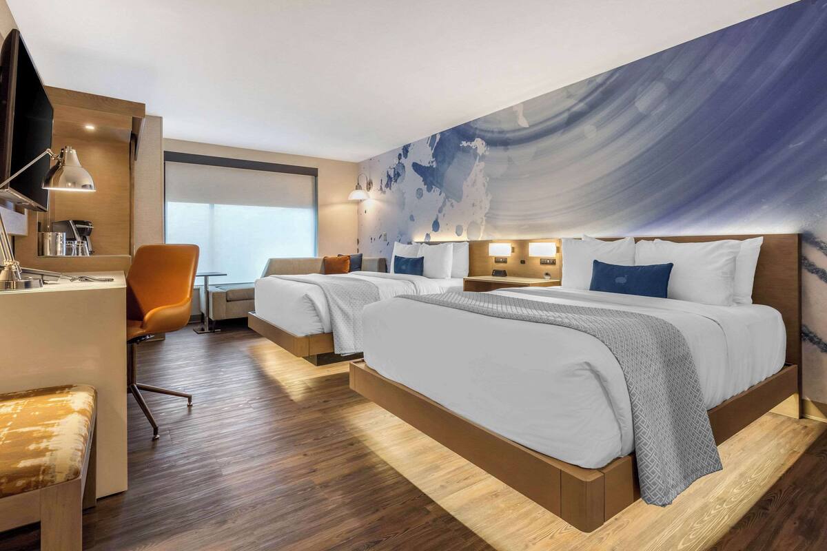 Hotellihuone, jossa on suuri sänky, työpöytä, tuoli ja televisio.