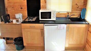 Een kleine keuken met een magnetron, koffiezetapparaat, spoelbak en een koelkast.