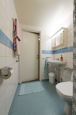 A compact bathroom with a toilet, sink, and towel rack. - Optimal Apartments Skärholmen (Skärholmen)