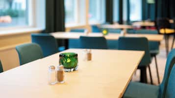A dining area with tables and chairs, salt and pepper shakers, and a green glass container.