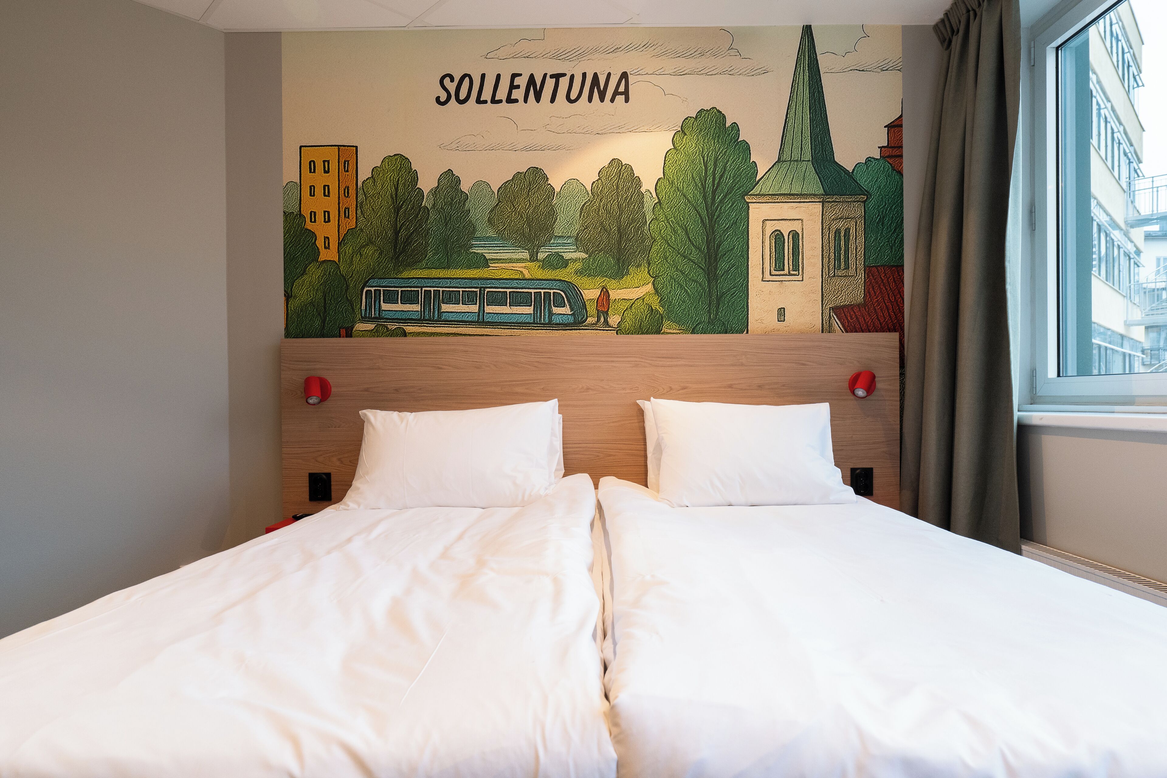 A hotel room with a bed, a headboard with a mural, and a window with curtains.