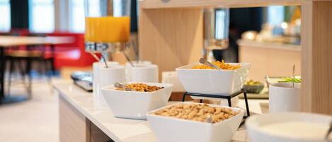 A breakfast buffet with various food items and a juice dispenser.