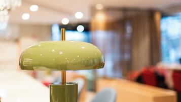 A close-up of a green lamp with a metallic base in a well-lit room with a blurred background.