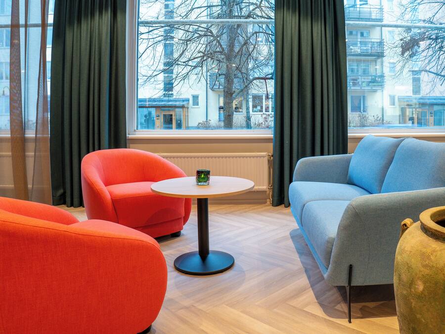 A modern living room with a sofa, armchair, and a round table.