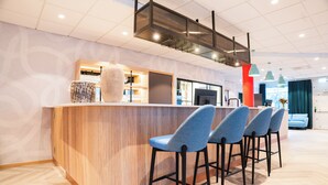 A modern bar area with a wooden counter, blue bar stools, and a large decorative vase. - Good Morning Sollentuna (Sollentuna)