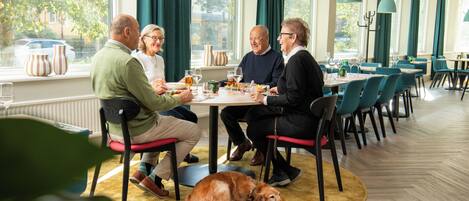 Un comedor con una mesa redonda, sillas y un perro acostado sobre una alfombra.