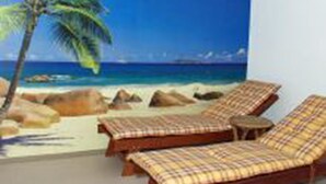 A room with a beach mural, two lounge chairs, and a small table. - Hotel-Gasthof Resengörg (Ebermannstadt)