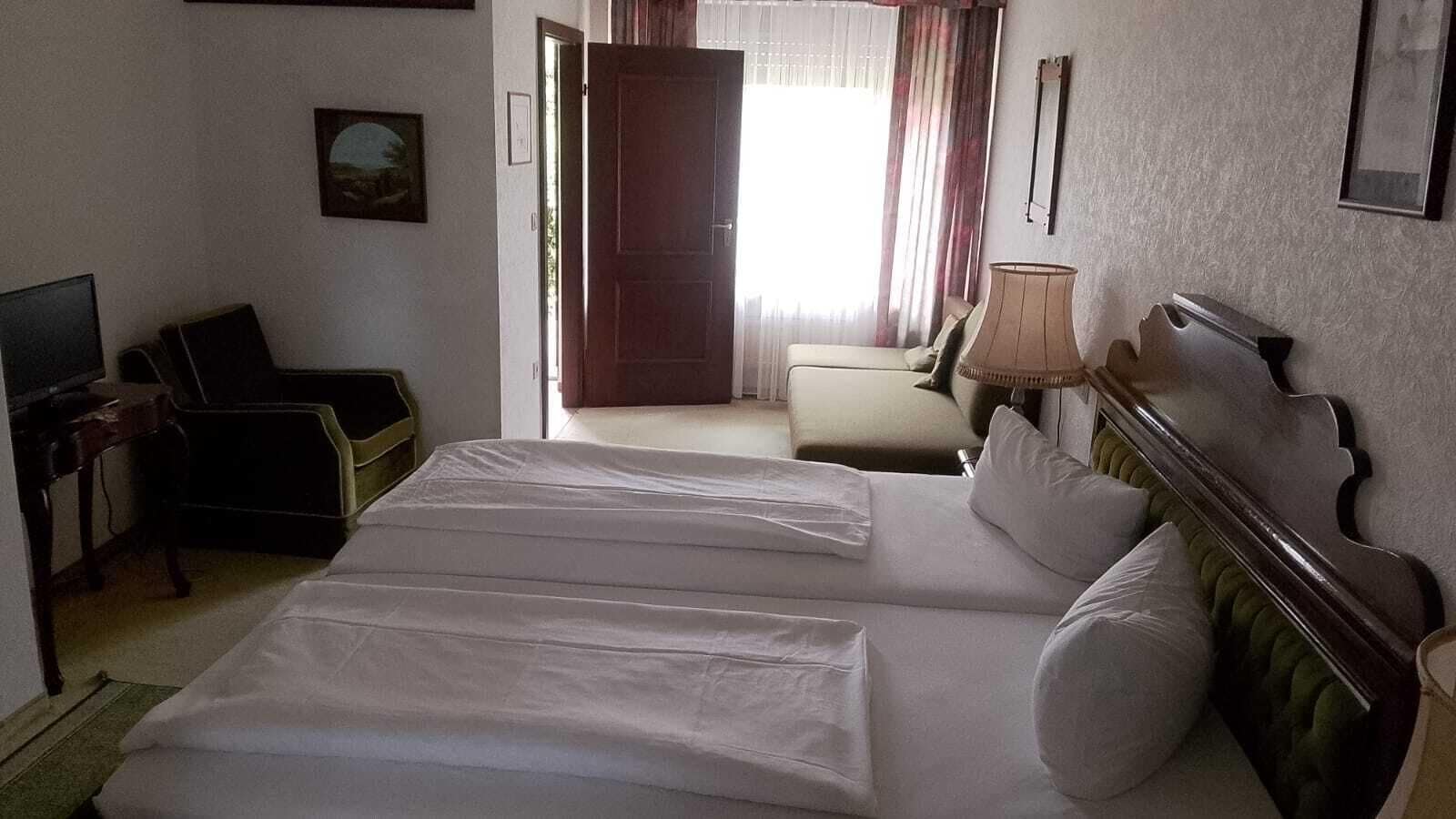 A hotel room with a bed, a desk, a chair, a lamp, and a picture on the wall.