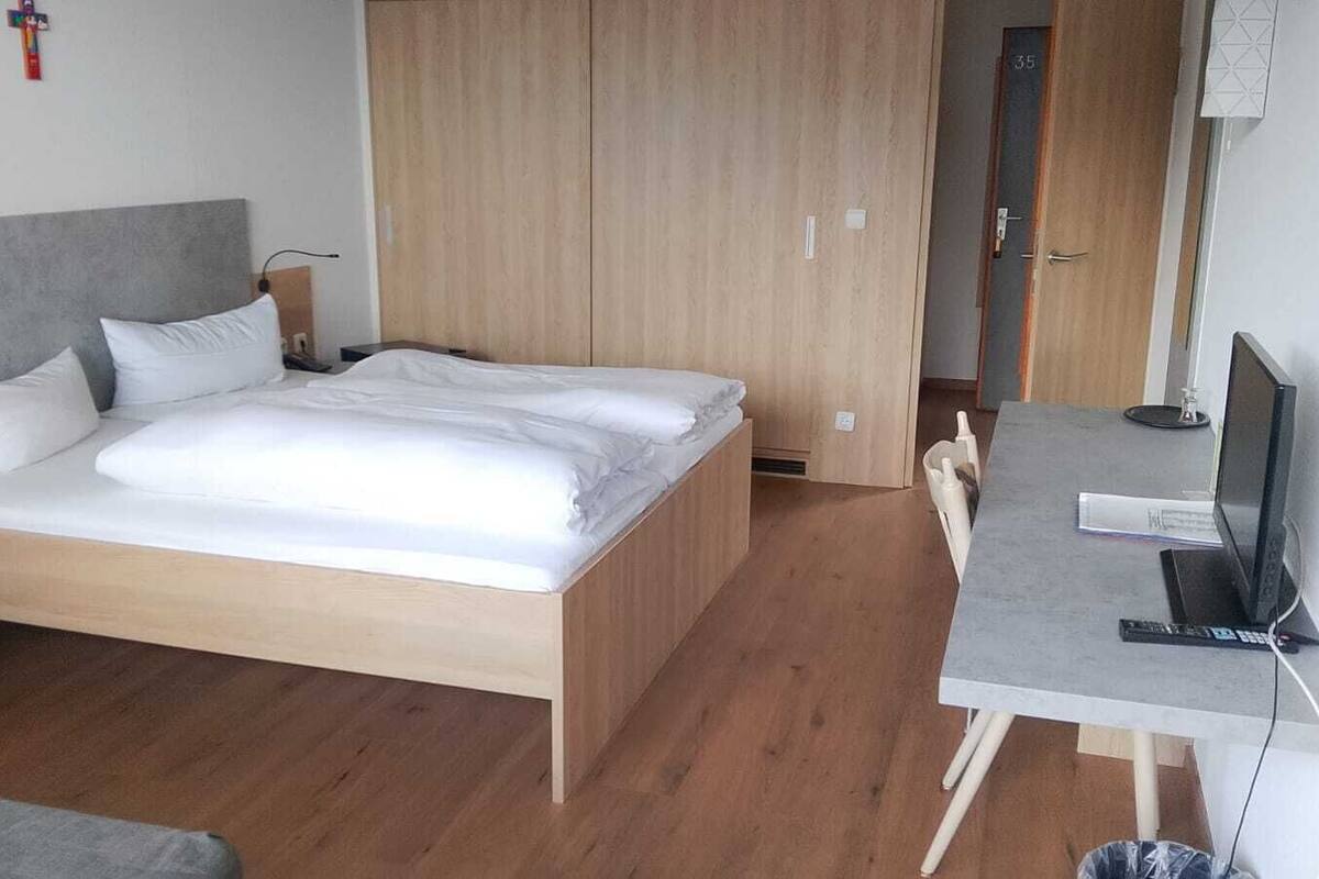 Ein Schlafzimmer mit Bett, Schreibtisch inklusive Computer und einem Kleiderschrank.