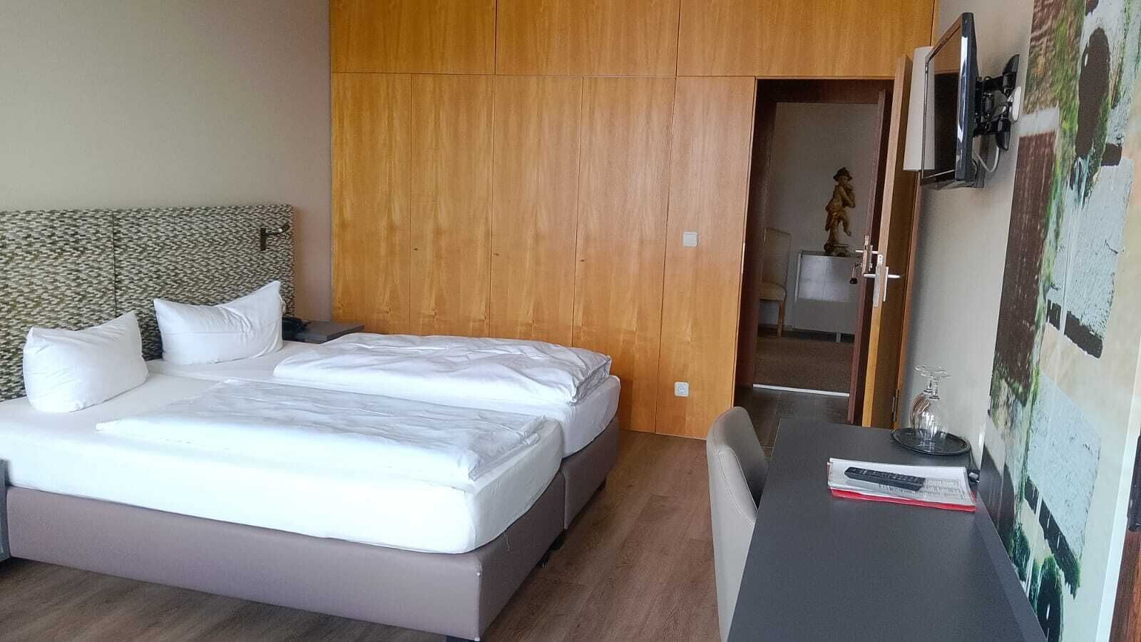 A bedroom with a bed, a desk, and a wardrobe.