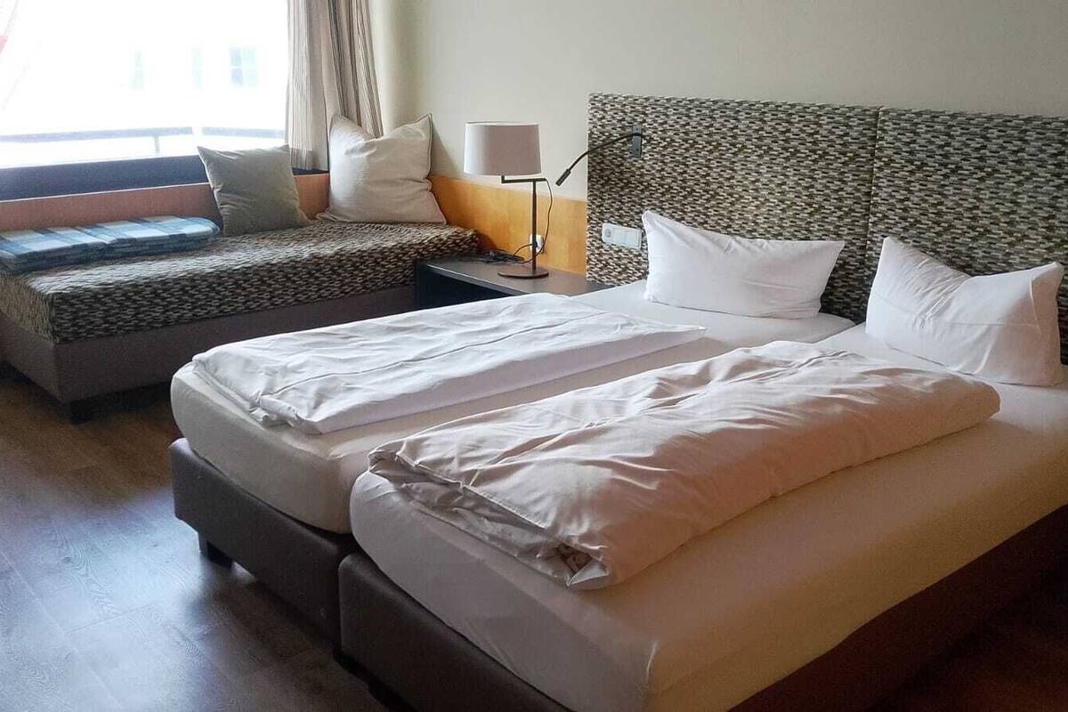 Ein Hotelzimmer mit Bett, Sofa, Nachttisch und Lampe.