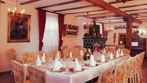 A dining room with a long table set for a meal, wooden beams on the ceiling, and a chandelier. - Hotel-Gasthof Resengörg (Ebermannstadt)