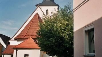 A cobblestone street leading to a church with a tall steeple and a cross on top.