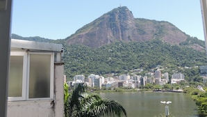 A view of a mountain with a prominent peak, a body of water, and a cityscape in the background. - Ótimo Flat 3 Quartos Vista Cristo Redentor (Rio de Janeiro)
