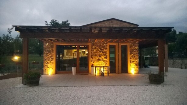 A modern building with a stone facade, large glass doors, and a covered entrance area.