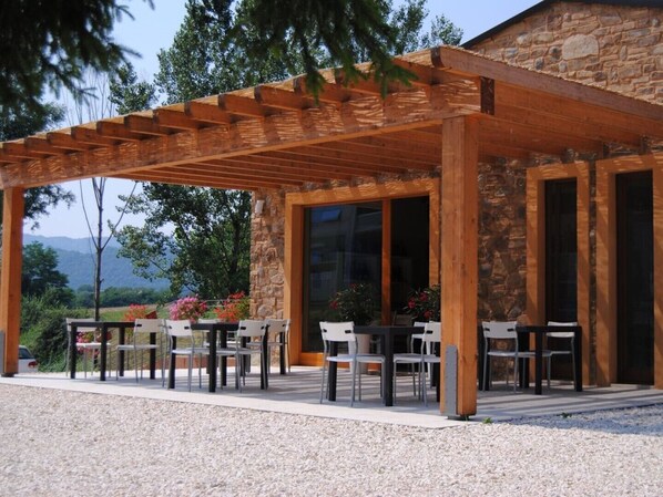 Une terrasse extérieure dotée d’une pergola en bois, de murs en pierre et offrant une vue sur les montagnes.