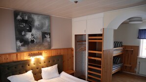 Un dormitorio con cama, cabecero, armario y literas.