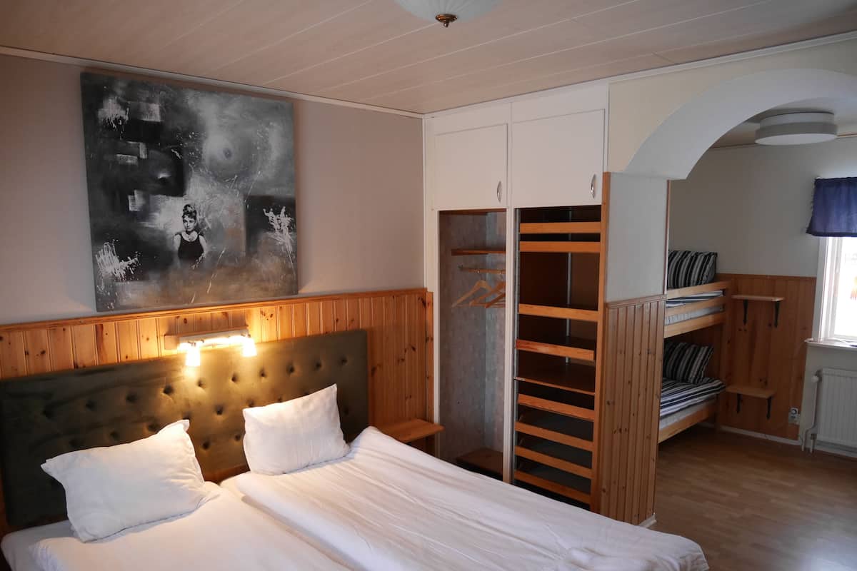 A bedroom with a bed, a headboard, a wardrobe, and a bunk bed.