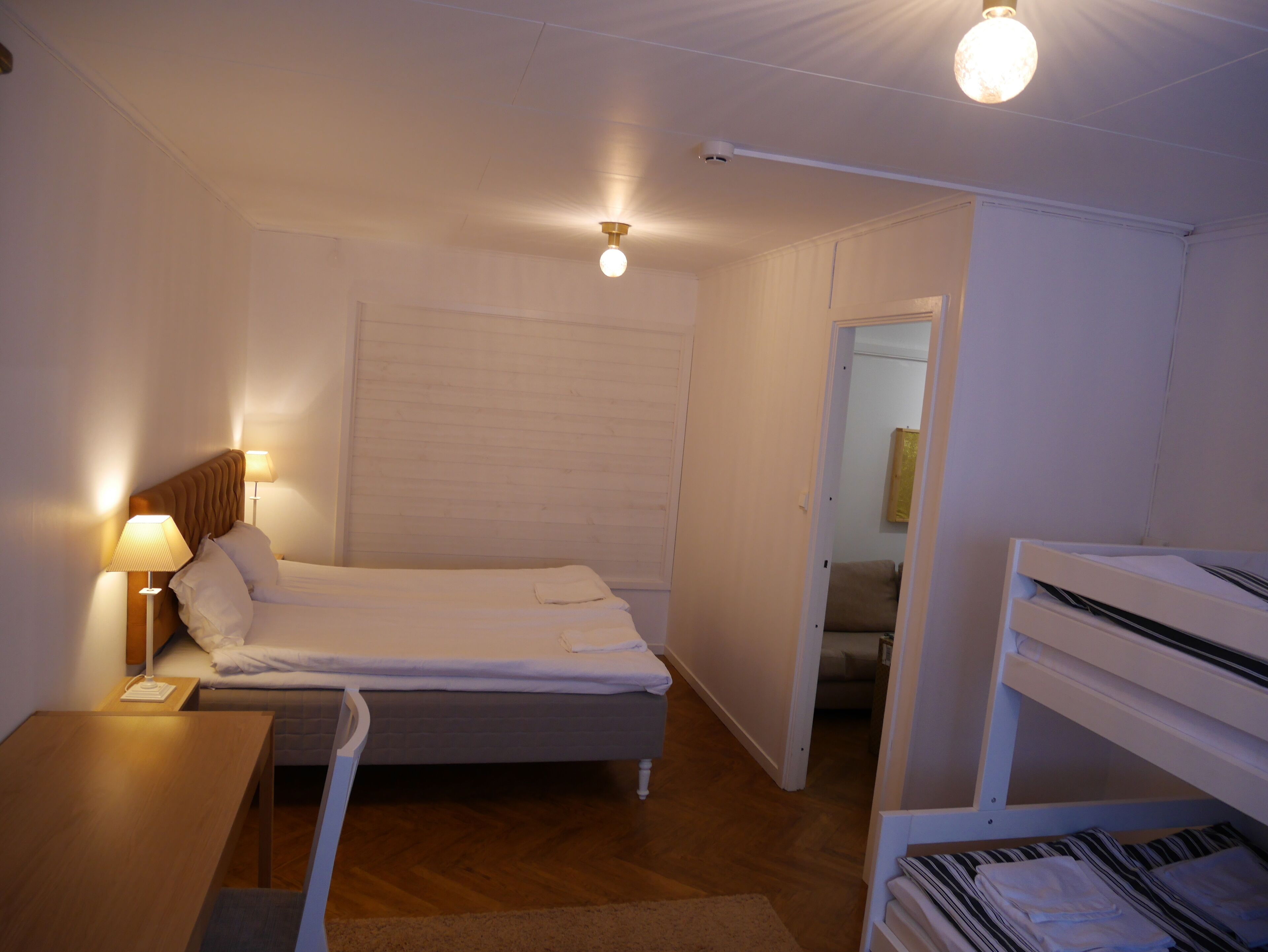 A bedroom with a single bed, bedside tables, a desk, and a bunk bed.