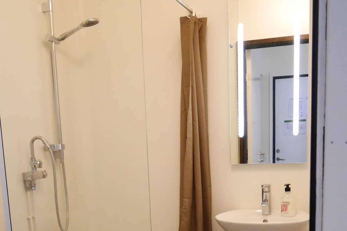 A bathroom with a shower, toilet, sink, and a mirror.