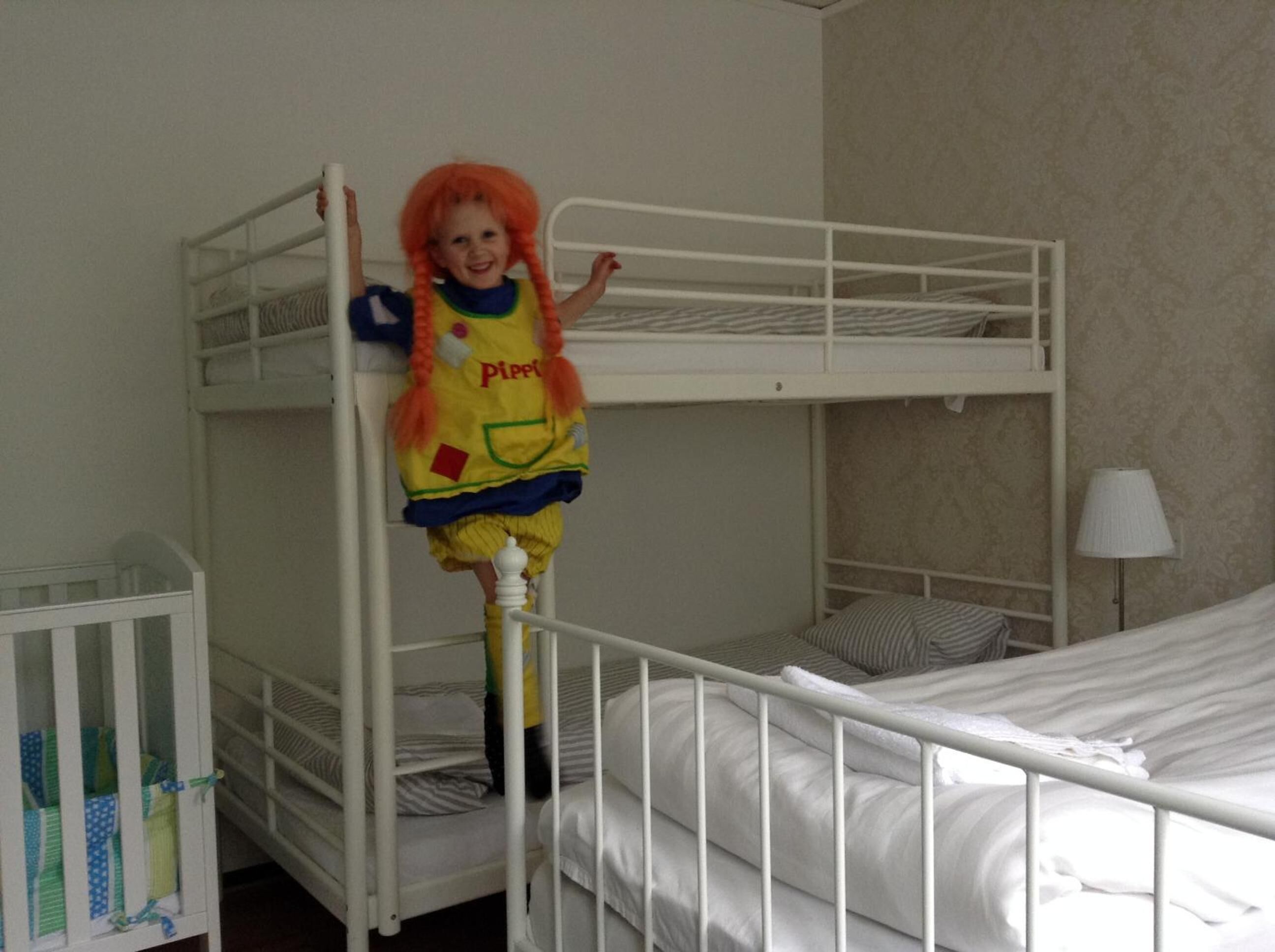 Habitación con literas y un niño de pie en la litera superior.