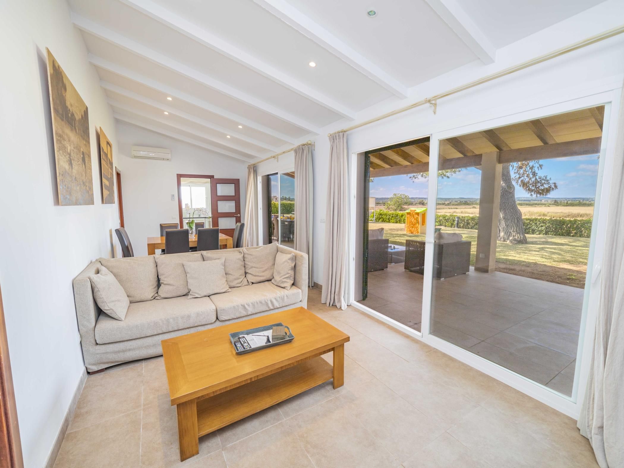 A spacious living room with a sofa, a coffee table, and a view of the outdoors through large sliding doors.