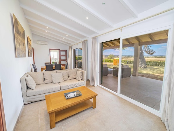 A spacious living room with a sofa, a coffee table, and a view of the outdoors through large sliding doors.
