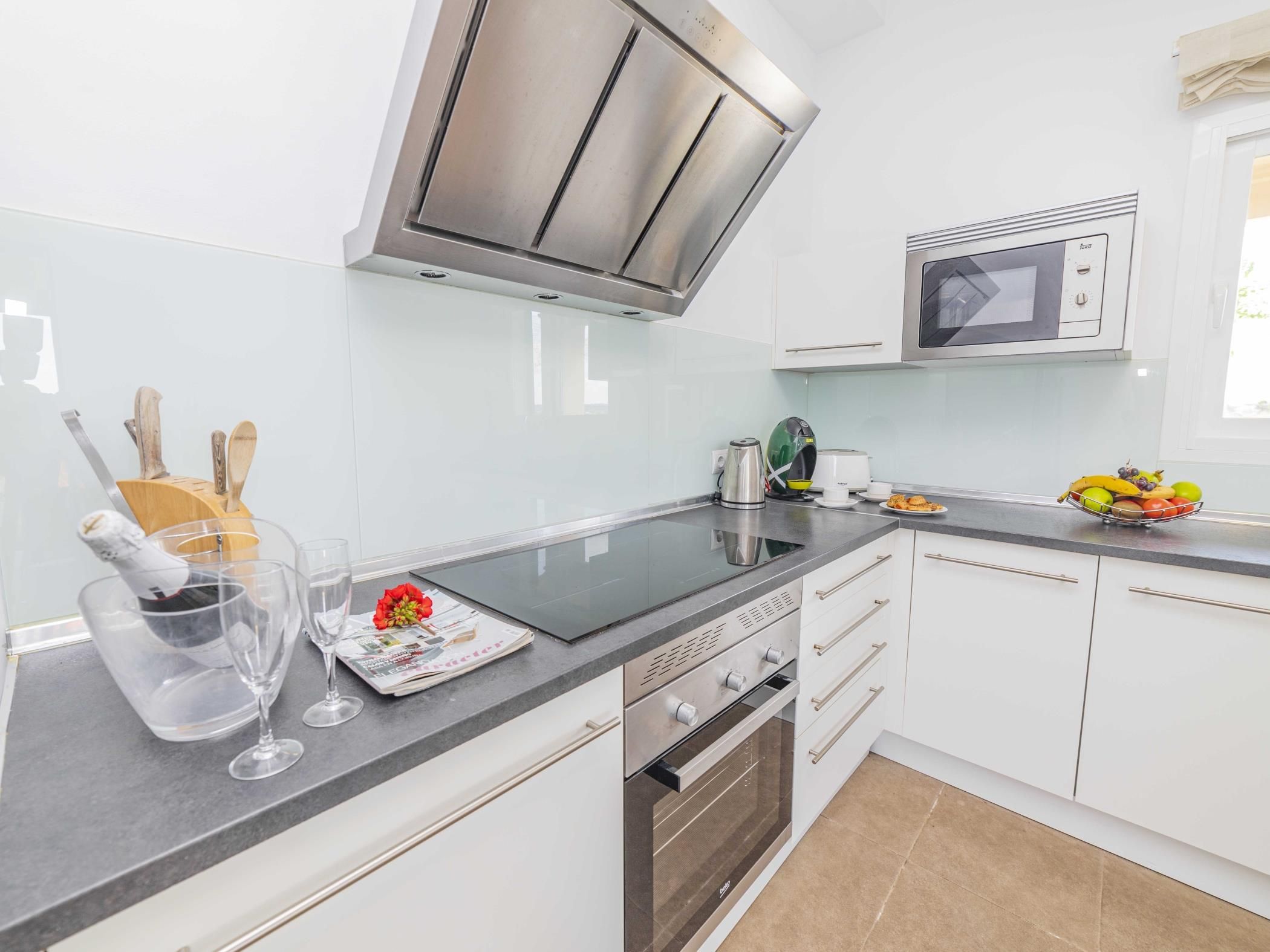 A modern kitchen with a built-in oven, a microwave, and a stainless steel range hood.