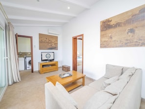 Ein Wohnzimmer mit einer Couch, einem Couchtisch, einem Fernseher und einem Bild an der Wand.