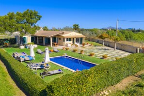 A residential property with a swimming pool, outdoor seating, and a well-maintained garden.