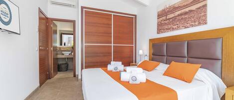 A hotel room with a bed, a nightstand, a bathroom visible through an open door, and a painting on the wall.