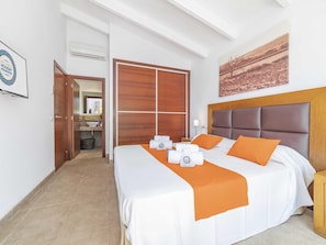 A hotel room with a bed, a nightstand, a bathroom visible through an open door, and a painting on the wall.